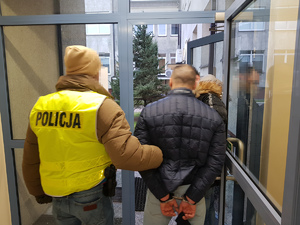 Zatrzymany 40-latek oraz policjanci wychodzą z pomieszczenia dla osób zatrzymanych